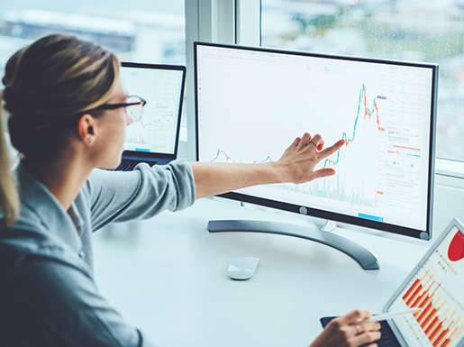 A woman looking and pointing at a chart on a computer screen