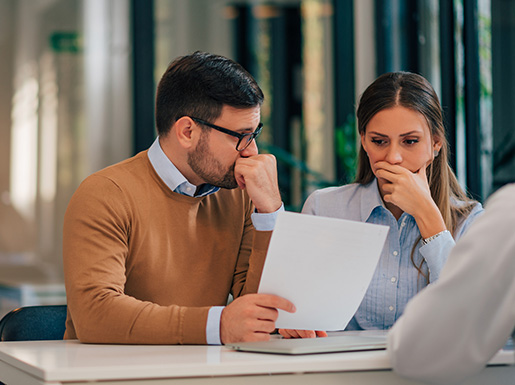 A man and woman sitting at a table looking at a piece of paper