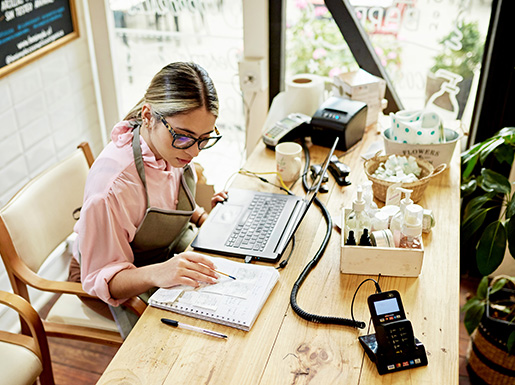 A worker sitting at a desk with a laptop and notebook