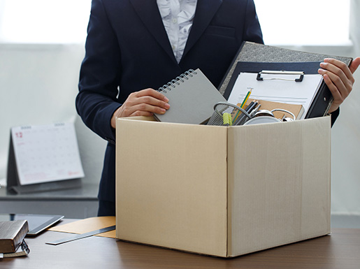 A worker at their desk with their items in a cardboard box