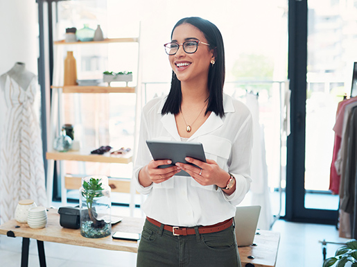 A woman smiling in store with tablet in hand